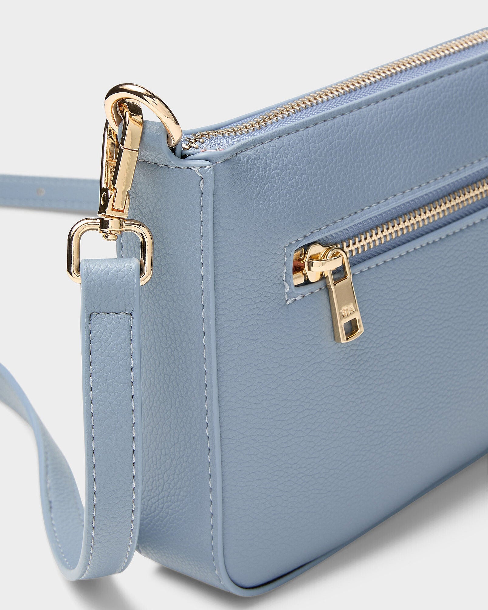 Light blue handbag with gold zipper and clasp on a light gray background
